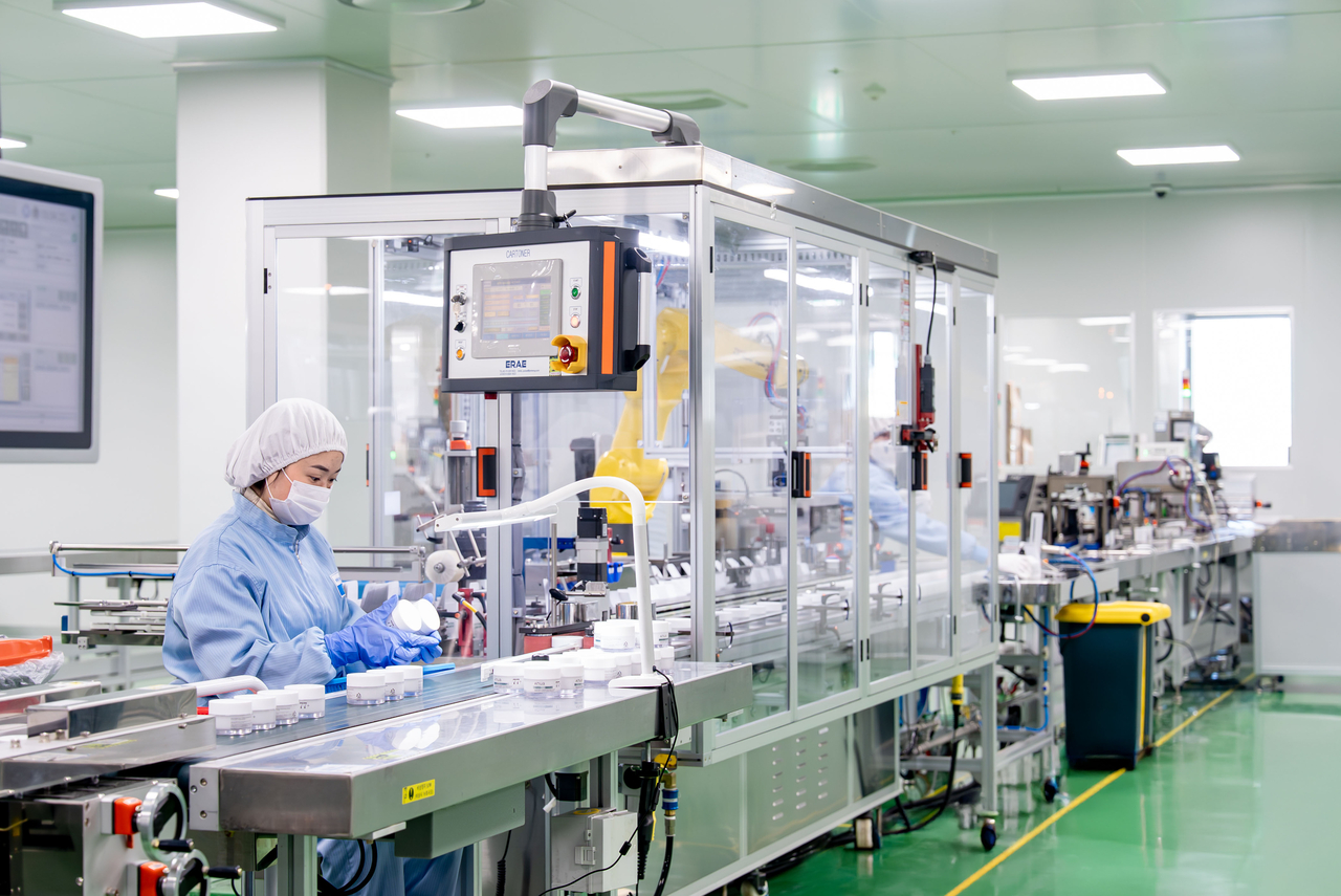 A worker and automated production equipment inside a manufacturing facility